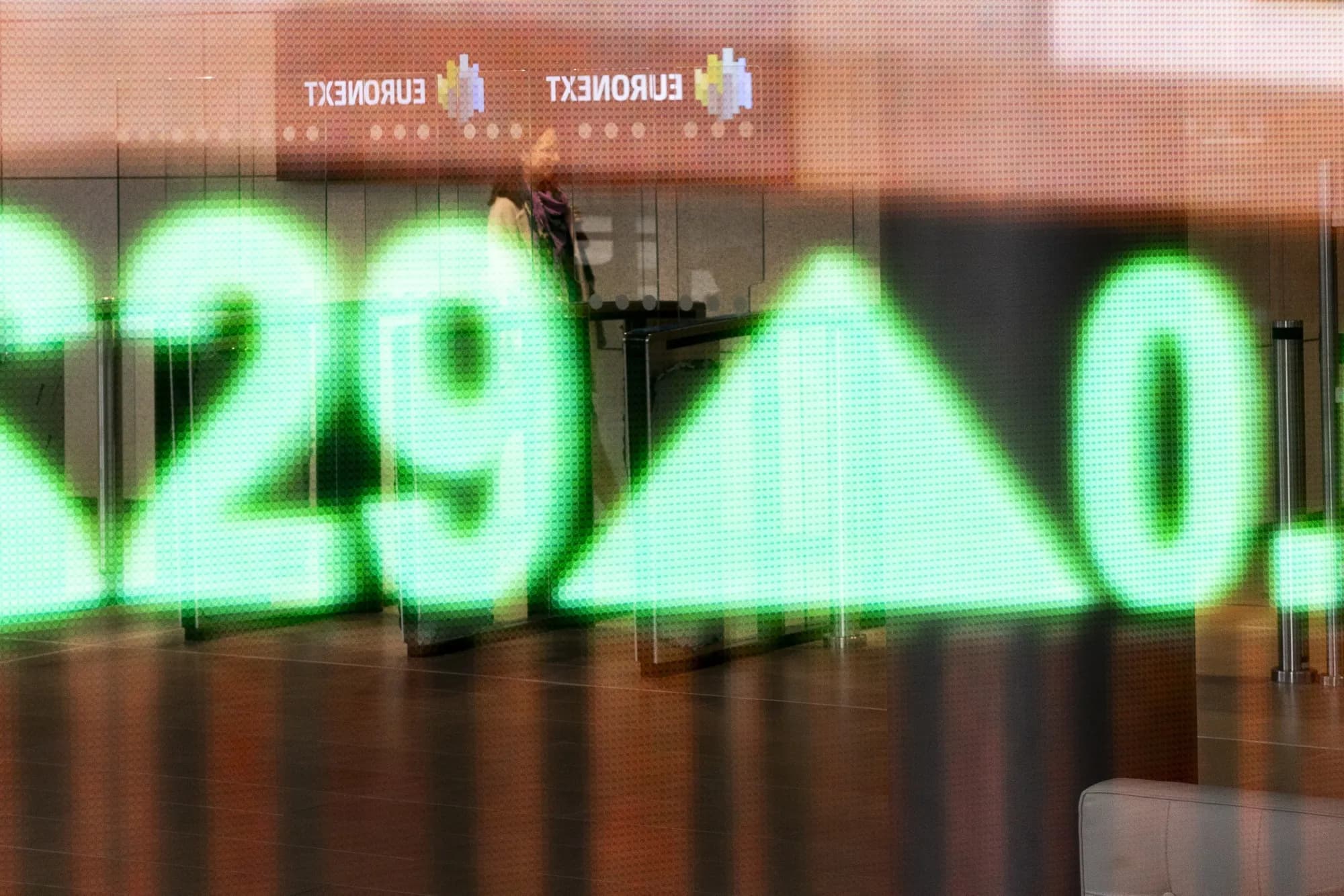 A blurred stock market ticker display showing a percentage figure in green, with the Euronext logo visible in the background.