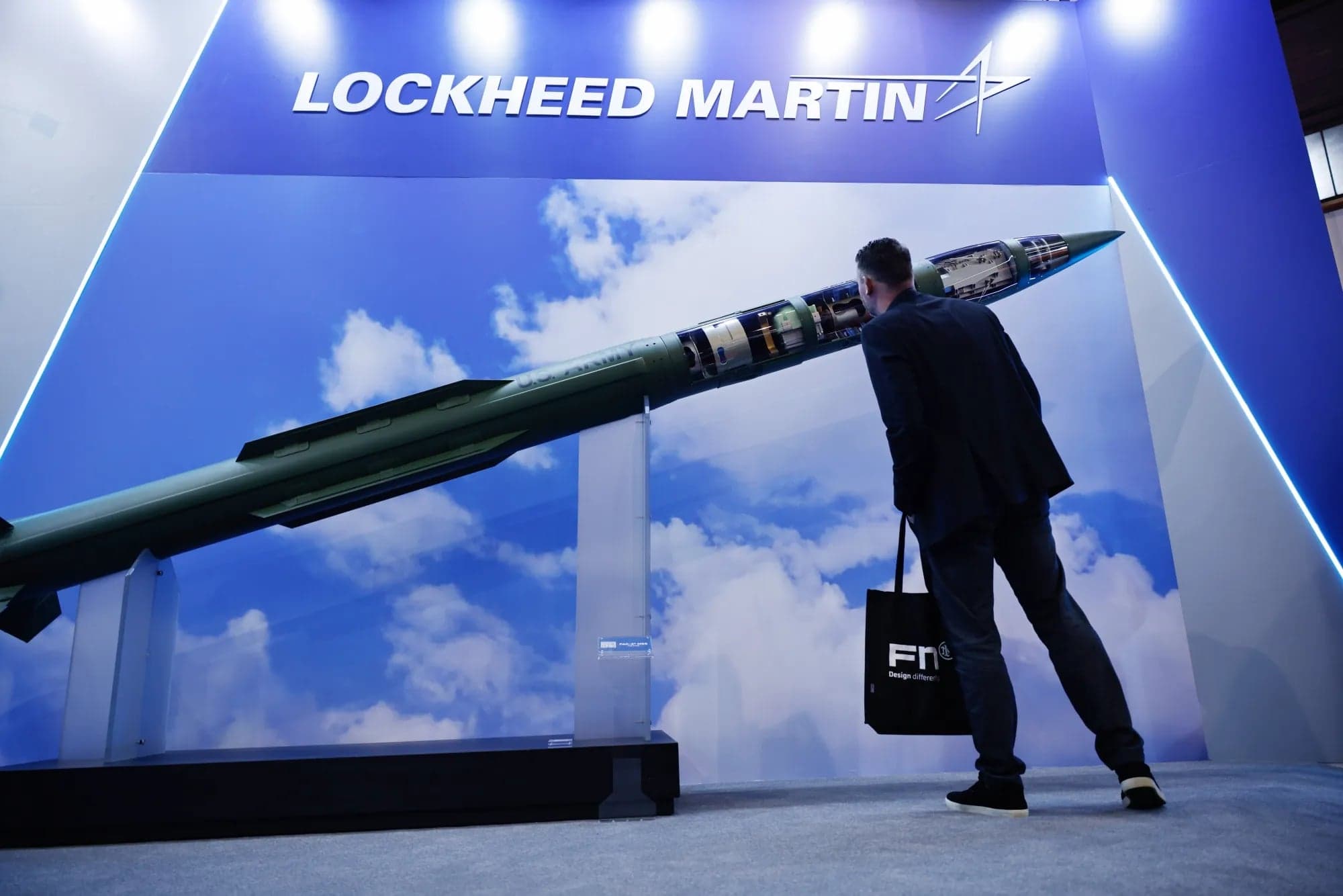 A man looking closely at a missile display at a Lockheed Martin exhibition booth